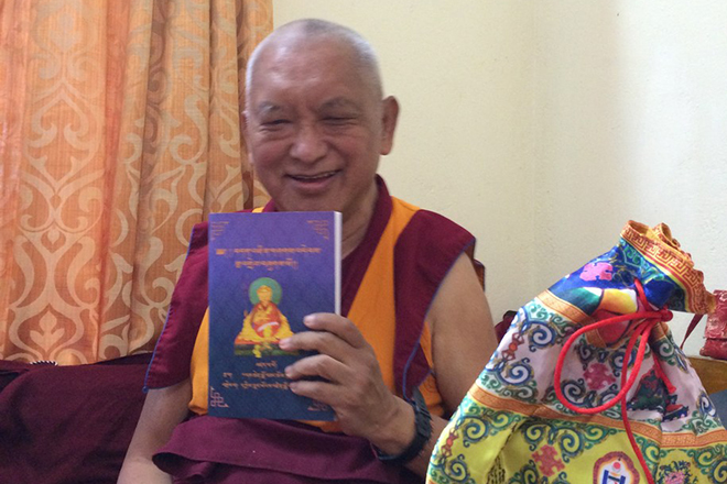 Kyabje Lama Zopa Rinpoche, displaying his copy of Panchen Lobzang Chokyi Gyaltsen's "Debate with Self-Grasping"